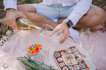 Obraz na płótnie Canvas man pouring champagne in glasses at picnic