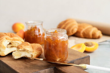 Jar of tasty apricot jam and croissant on table