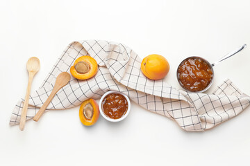 Bowls of tasty apricot jam on white background