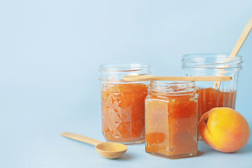 Jars of tasty apricot jam on color background