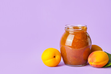 Jar of tasty apricot jam on color background