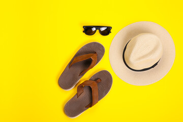 Male flip-flops with hat and sunglasses on color background