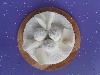 Coconut cake with white chocolate on a a lilac background with a sprinkle of coconut shavings