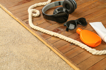 Obraz na płótnie Canvas Male sunglasses with headphones and sunscreen on sand