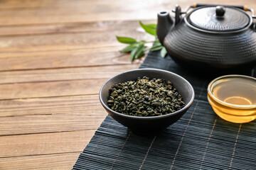 Bowl with dry tea leaves, teapot and honey on table