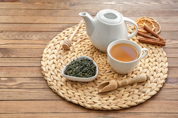 Cup of tea with dry leaves and teapot on table