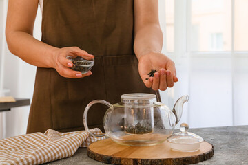 Fototapeta na wymiar Woman brewing green tea in pot at home