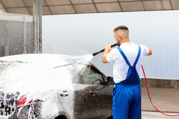 Male worker washing car outdoors