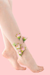Woman's thin unshaven leg with pink flowers on a pink background. Feminism