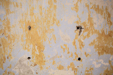 Worn and shabby wall surface with four holes, background