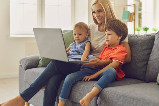 Young mom and kids using laptop to watch educational cartoons or to video chat with relatives