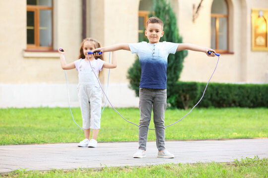 Cute little children jumping rope outdoors
