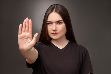 Female protest. Feminism empowerment. Confident overweight woman in black t-shirt showing stop...