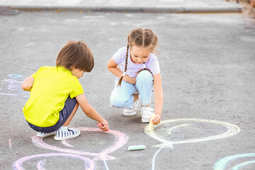 Little children drawing with chalk on asphalt