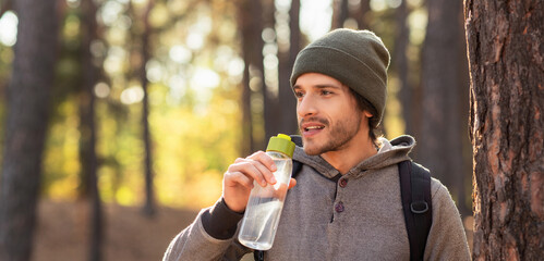 Closeup of young man drinking water in forest