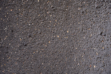 Abstract background of black wet asphalt with inclusions of pebbles