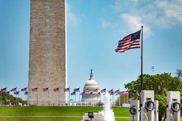 WWII and Washington memorial obelisk column over flags, US Capitol building, DC, USA