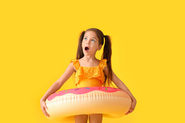 Surprised little girl with swimming ring on color background