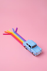 Blue car toy with rainbow trail make from straws. Minimal pop art travel concept. Flat lay.