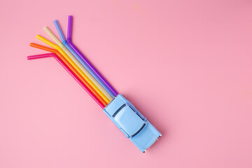 Blue car toy with rainbow trail make from straws. Minimal pop art travel concept. Flat lay.