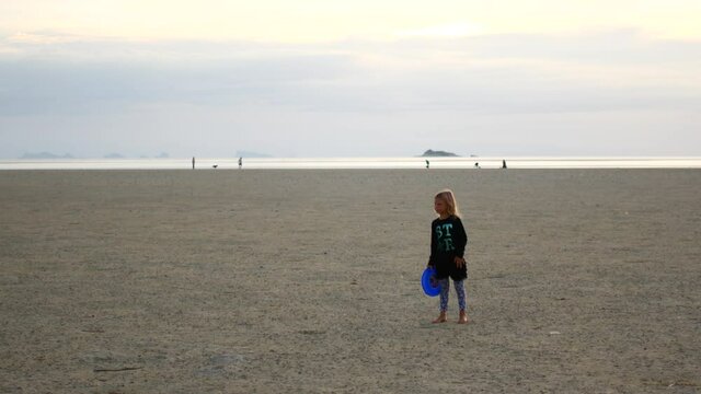 Little girl throwing sports equipment on the beach