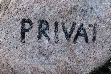 Bright granite erratic block with the faded inscription private to mark the end of the public area