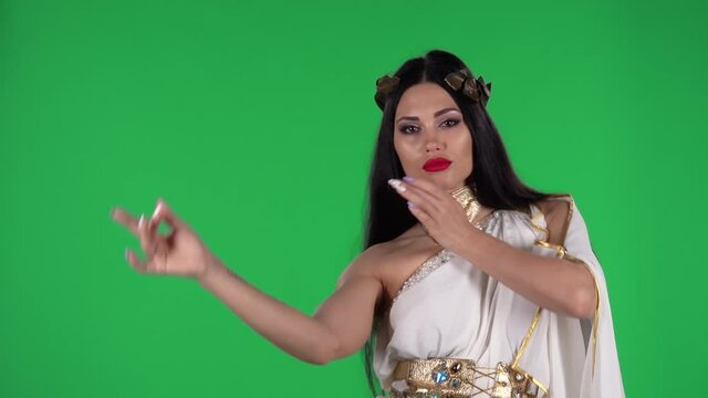 Portrait of beautiful woman in greek greece goddes dress and wreath high fashion is looking straight and dancing. Green screen.