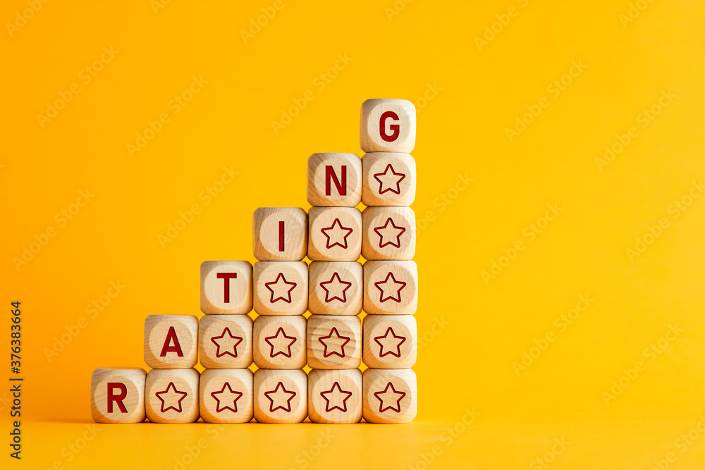 Poster the word rating with increasing performance stars on wooden cubes against yellow background. improve