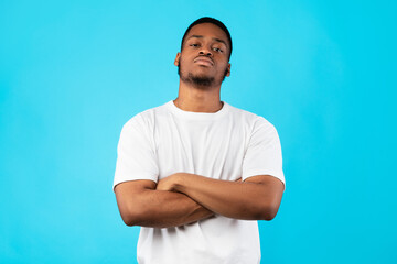 Fototapeta premium Cool Black Man Standing Crossing Hands Posing On Blue Background