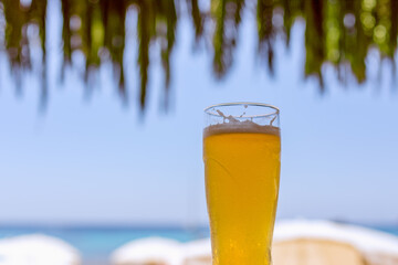 Cold beer in a glass at a beach bar overlooking the sea