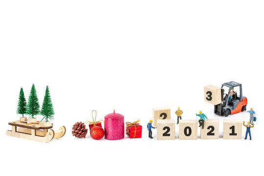 miniature worker team building standing front of forklift machine with   2021 number on wooden block on white background decoration to Happy new year 2021 concept.