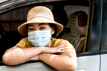 Young Asian women wear a mask due to air pollution or a viral epidemic before traveling in their car. Virus protection concept