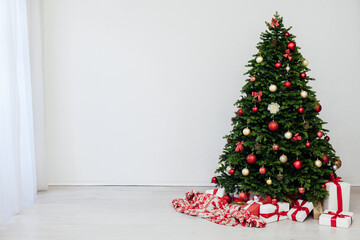 The interior of the white room is a green Christmas tree with red gifts for the new year holiday decor