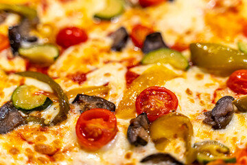 Close up of delicious Italian vegetable cheese pizza showing its vegetable toppings, tomato, mushroom, bell pepper, and cheese