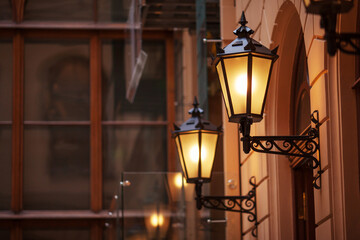 Fototapeta na wymiar Old fashioned street lamp at night. Brightly lit street lamps at sunset. Decorative lamps. Magic lamp with a warm yellow light in the city twilight