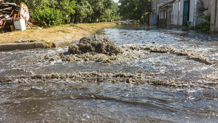 Water flows out of drainage hatch. Drainage fountain of sewage. Accident in sewage system. Dirty...