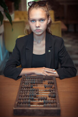 The girl is sitting at a table with old accounting accounts