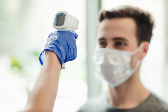 Manager checking body temperature of man with contactless thermometer