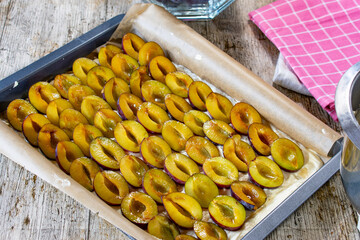 Raw plum cake on a baking sheet