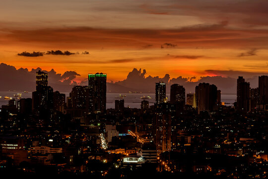 Skyline of Manila and Manila Bay during a fiery orange sunset. Near silhouette image of city. Bataan visible at the back.