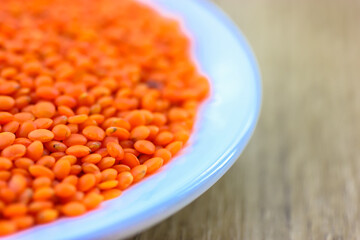 Red lentils in a round white plate: ingredients for a healthy diet natural meal