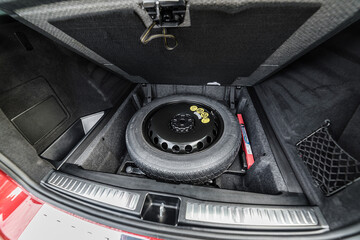 A spare tyre with warnning triangle in a trunk.