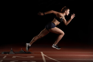 Woman Sprinter in Mid Action Bursting From Blocks During Race
