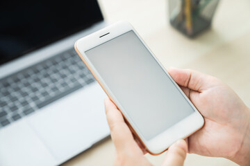 Woman hand holding smartphone and touching blank screen. Mockup of advertisement.