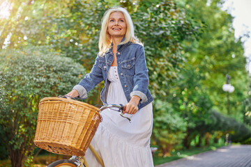 Pretty blonde woman with bicycle in a park