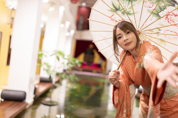 Asian beautiful woman in traditional Japanese kimono with an umbrella  and smiling at camera,...