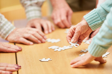Hand of a senior citizen holds a piece of the puzzle