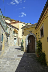 A small road crosses the old buildings of Catelmezzano, a rural village in the Basilicata region, Italy.

