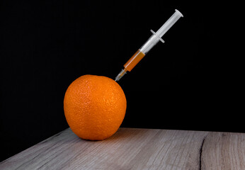Bright orange on a wooden board and syringe inside it extracting orange liquid