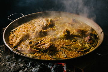 cooking a paella over a wood fire. Valencia Spain - obrazy, fototapety, plakaty